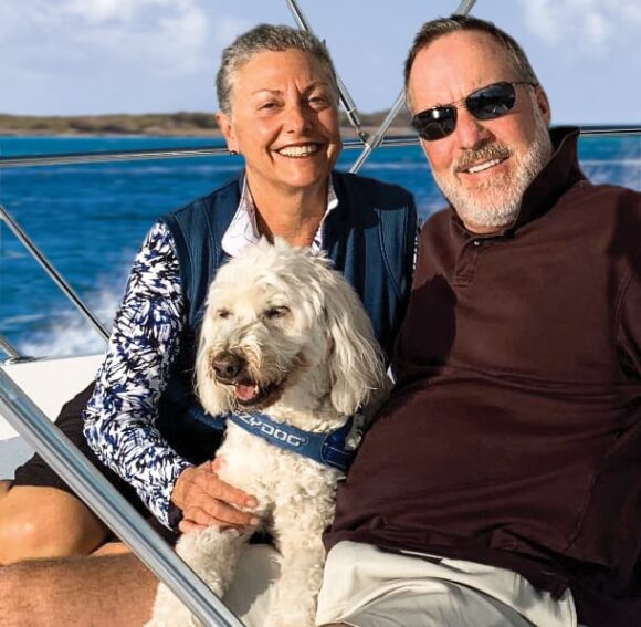 Smiling couple on boat with white dog