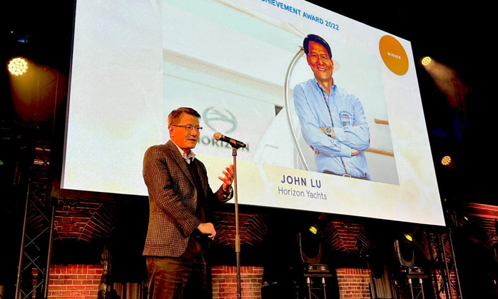 A man receiving a lifetime achievement award while standing in front of a large screen.