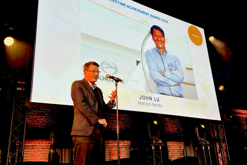 A man receiving a lifetime achievement award while standing in front of a large screen.