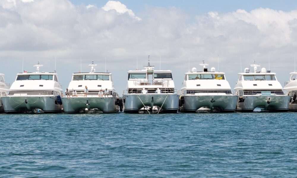 Five white yachts docked in blue water.