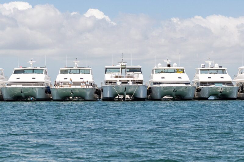 Five white yachts docked in blue water.