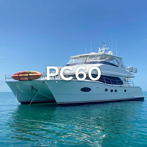 White PC60 catamaran docked in water.